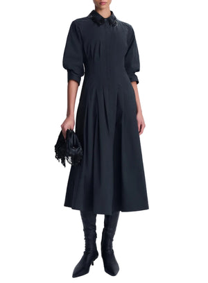 A black cotton poplin Jazz Embellished Collar Midi Dress by Simkhai with three-quarter sleeves, worn with black knee-high boots and a beaded fringe clutch.