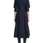 Back view of the black Jazz Embellished Collar Midi Dress by Simkhai featuring an embellished collar, three-quarter sleeves, a pleated skirt, and black boots.