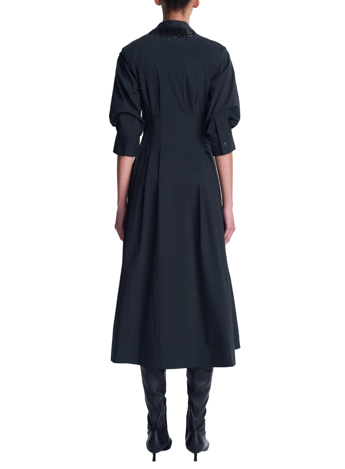 Back view of the black Jazz Embellished Collar Midi Dress by Simkhai featuring an embellished collar, three-quarter sleeves, a pleated skirt, and black boots.