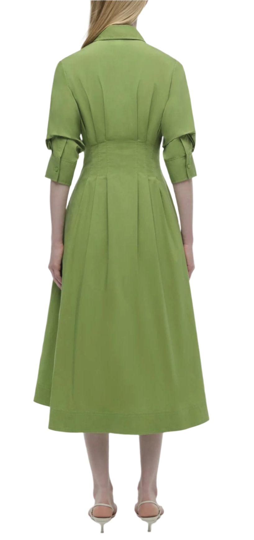 A person is seen from the back wearing the Simkhai Signature Jazz Dress, a green pintuck midi dress with elbow-length sleeves and a fitted waist, paired with beige sandals.