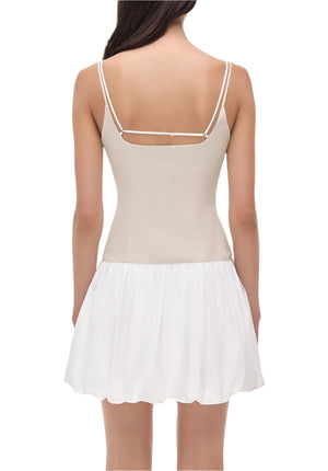 Woman shown from the back wearing the Simkhai Fifi Mini Dress—a sleeveless, light beige linen poplin mini with thin straps and a white, gathered skirt above the knee.
