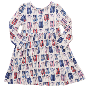 The Girls' Bamboo Steph Dress by Pink Chicken features long sleeves, a gathered waist, and a playful print of pink, red, and blue ballet shoes on soft white bamboo fabric.