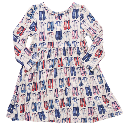 The Girls' Bamboo Steph Dress by Pink Chicken features long sleeves, a gathered waist, and a playful print of pink, red, and blue ballet shoes on soft white bamboo fabric.