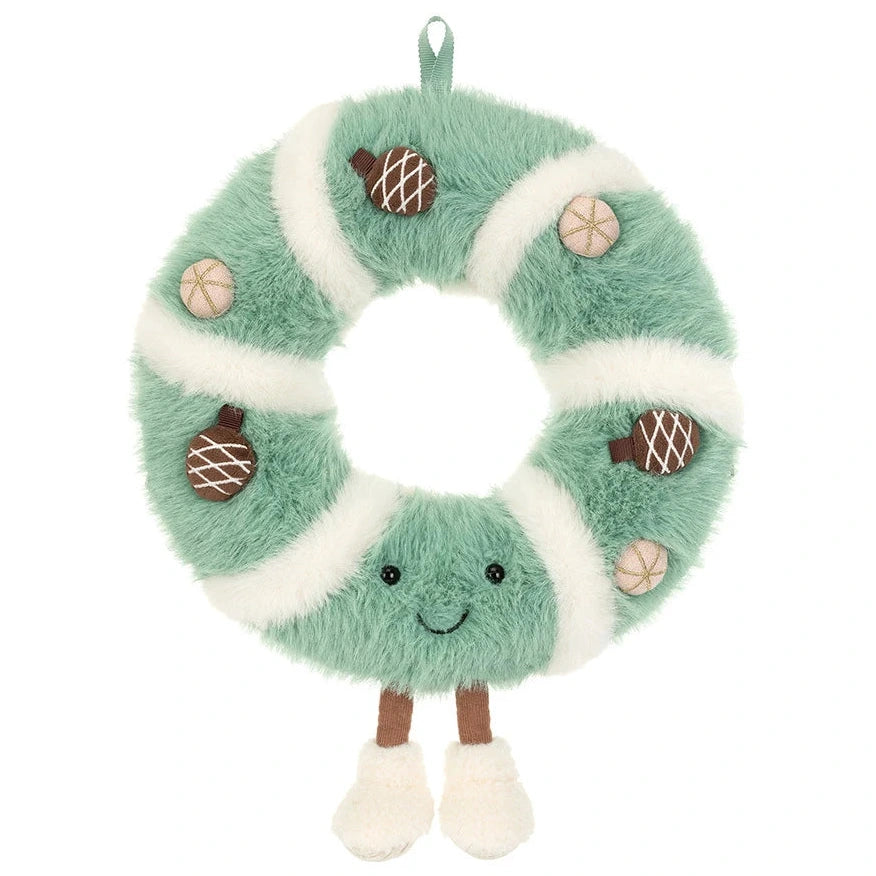 A plush, circular Jellycat Amuseables Pinecone Wreath with a smiling face, dangling legs, and decorative berry accents.