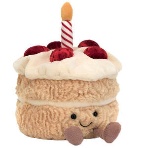 The Jellycat Amuseables Birthday Cake is a plush slice with a smiling face, soft strawberries, white icing, and a red-and-white striped candle—perfect for birthday celebrations.