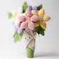 A plush Jellycat Amuseables Bouquet of Flowers featuring pastel-colored blooms wrapped in fabric with a smiling face.