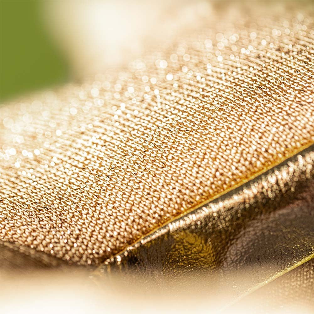 Close-up of golden, textured fabric with a glittery, metallic look, inspired by the dazzling style of Jellycat's Amuseables Zapperty Lightning Bolt plush toy.