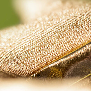 Close-up of golden, textured fabric with a glittery, metallic look, inspired by the dazzling style of Jellycat's Amuseables Zapperty Lightning Bolt plush toy.
