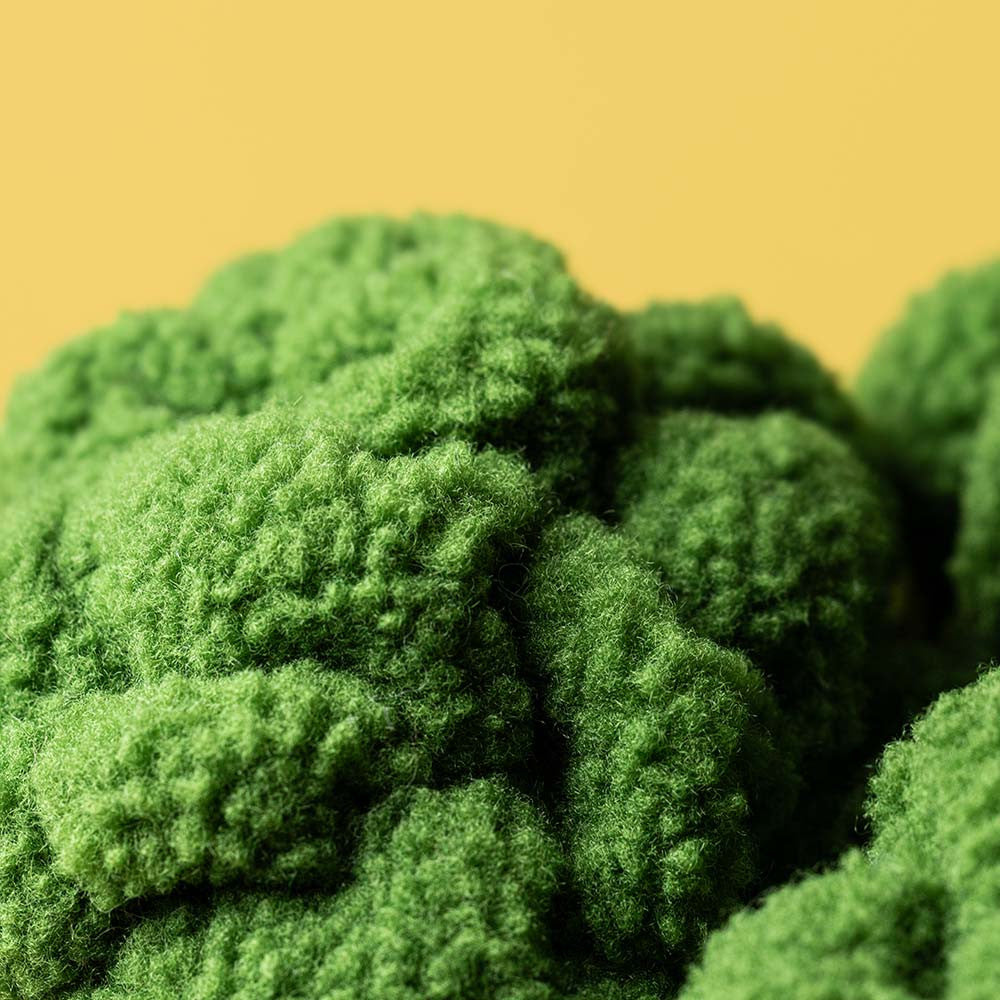 Close-up of Jellycat’s Amuseables Broccoli plush, featuring textured green fabric that resembles broccoli, set against a solid yellow background.