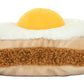 Meet Jellycat’s Amuseables Egglantine Egg on Toast—a plush toy shaped like toast with a fried egg, made from soft brown, white, and yellow fabrics.