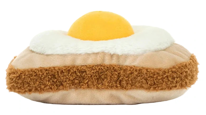 Meet Jellycat’s Amuseables Egglantine Egg on Toast—a plush toy shaped like toast with a fried egg, made from soft brown, white, and yellow fabrics.