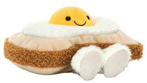 The Jellycat Amuseables Egglantine Egg on Toast is a plush toy shaped like egg on toast, featuring a smiling yellow yolk, white and brown details, and small feet at the bottom.