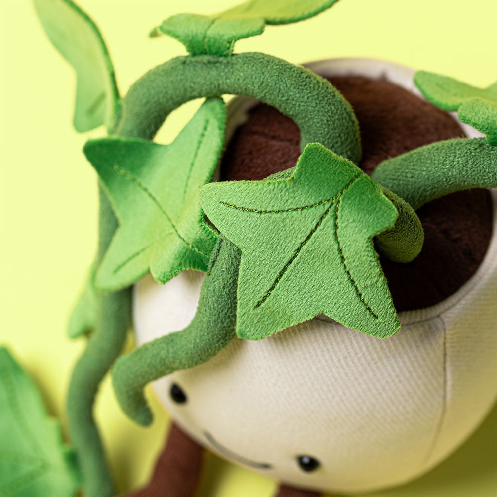 Jellycat’s Amuseables Ivy is a plush toy shaped like a plant pot with green leaves and vines on top and a smiling face—an ideal friendship gift, pictured on a cheerful yellow background.