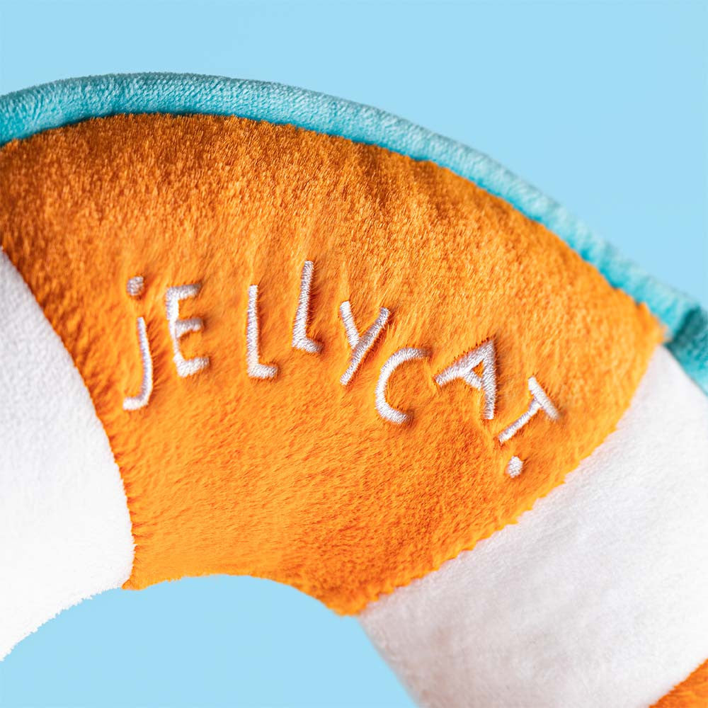 Close-up of the Jellycat Life Ring plush, showing orange, white, and teal sections with "JELLYCAT" embroidered in white on the orange band.