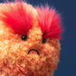 Close-up of the Jellycat Amuseables Planet Mars plush, showing its bright red eyebrows and frowning mouth, against a plain dark blue background.