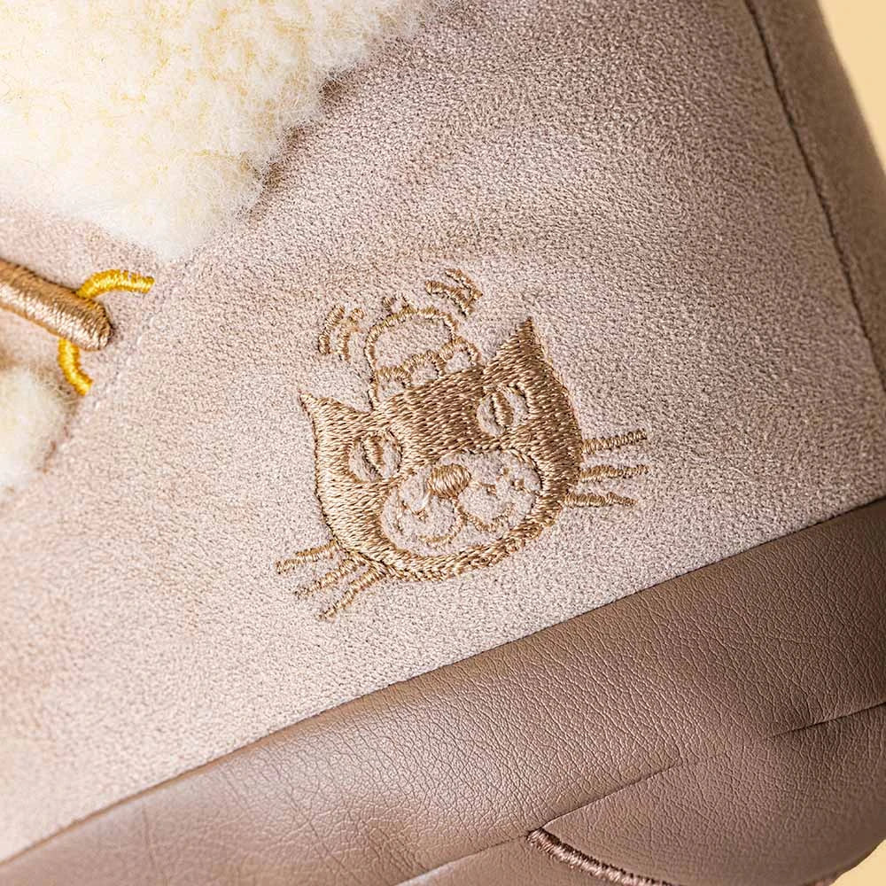 Close-up of the Amuseables Perta Snow Boot by Jellycat, featuring a stitched cat face, bee detail, fuzzy white lining, and visible stitching—ideal for Christmas décor.
