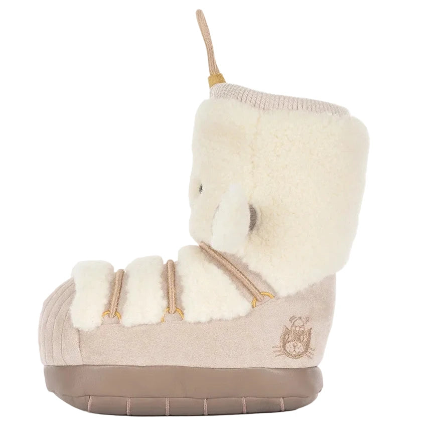 The Amuseables Perta Snow Boot by Jellycat is a plush, beige slipper with a ribbed sole, faux fur cuff, ear accents, and an embroidered cat face on the heel.