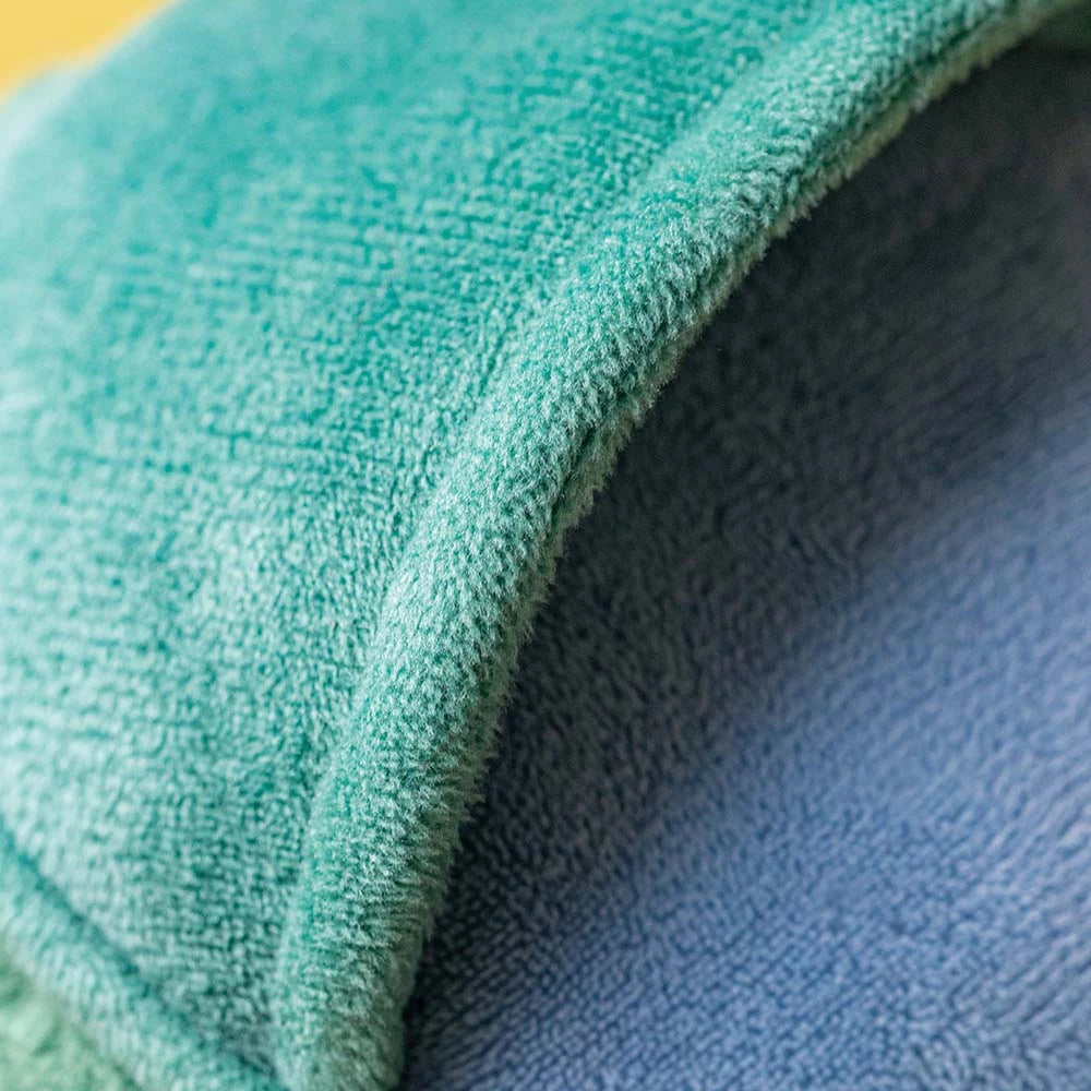 Close-up of a soft, teal and blue fabric tunnel with a textured surface, echoing the playful design of the Amuseables Watering Can by Jellycat. Likely part of a pet bed or play structure.