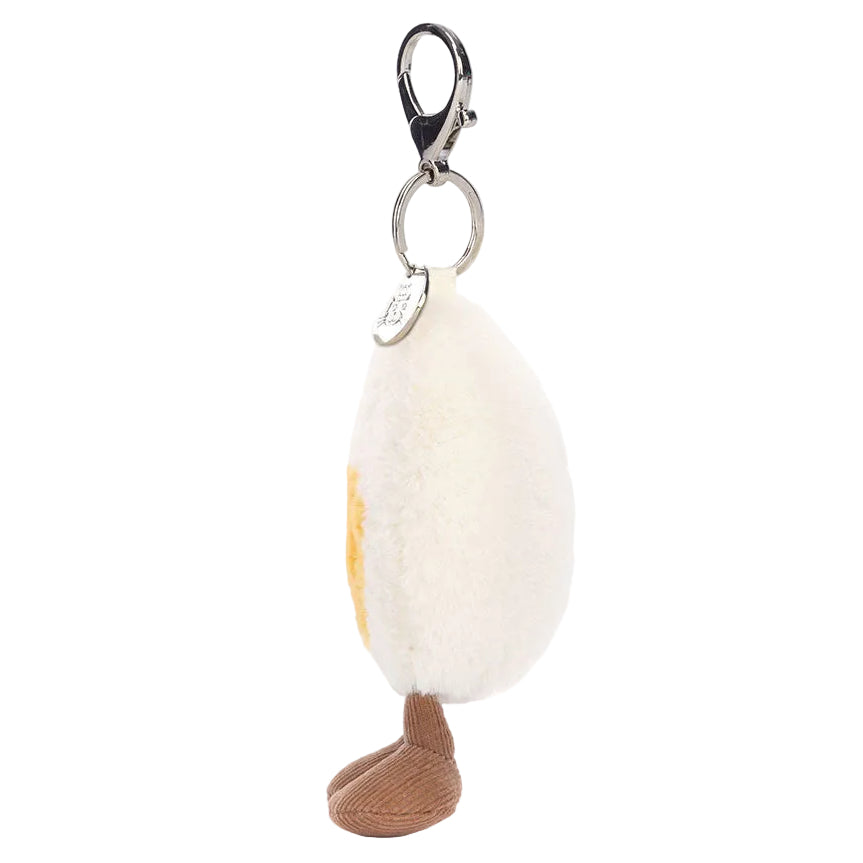 The Jellycat Amuseables Happy Boiled Egg Bag Charm is a plush keychain with a smiling egg and brown legs, attached to a metal keyring and clasp.