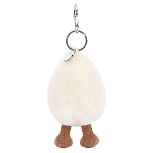 The Amuseables Happy Boiled Egg Bag Charm by Jellycat features a fluffy, egg-shaped design with brown knitted legs and a silver keyring on top.