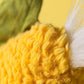 Close-up of the textured yellow plush from Jellycat’s Amuseables Sweetcorn, featuring a tuft of white fibers and a hint of green fabric in the background.