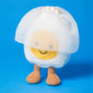 The Jellycat Amuseables Boiled Egg Bride is a plush toy with a smiling face, brown legs, and a white mesh veil—great for Jellycat enthusiasts and collectors of cute, unique plushies.