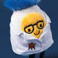 The Jellycat Amuseables Boiled Egg Scientist Outfit is a plush with a yellow face, black glasses, blue hair, and a white lab coat featuring a small embroidered bug logo.