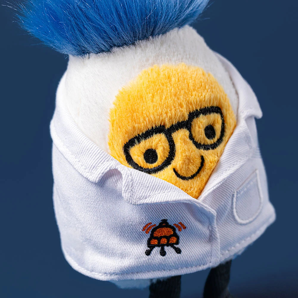 The Jellycat Amuseables Boiled Egg Scientist Outfit is a plush with a yellow face, black glasses, blue hair, and a white lab coat featuring a small embroidered bug logo.