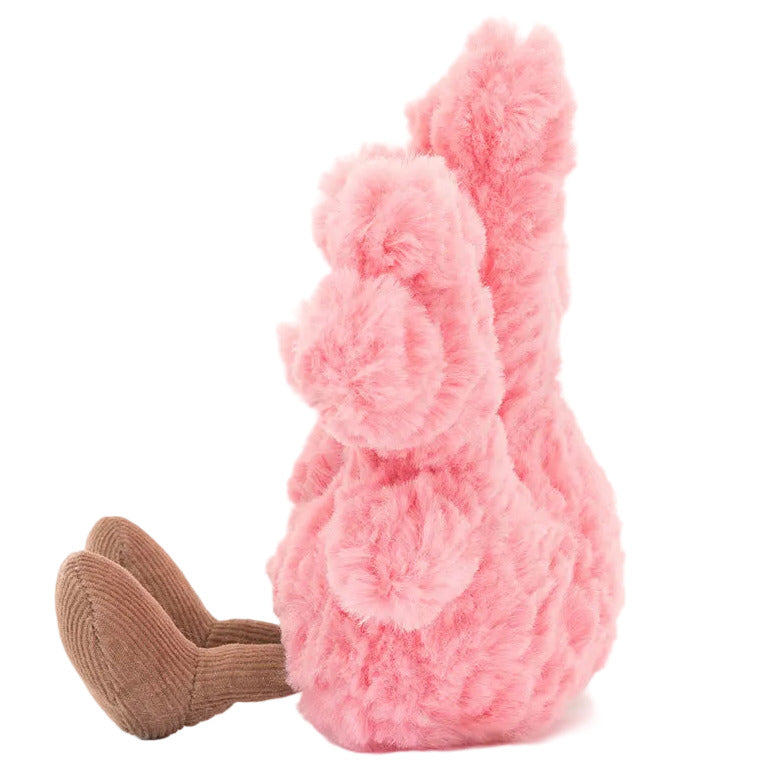 Side view of a pink Jellycat Amuseables Coral plush toy with brown dangling legs.