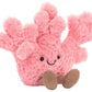 Plush pink Jellycat Amuseables Coral toy with a smiling face and small brown dangling legs.