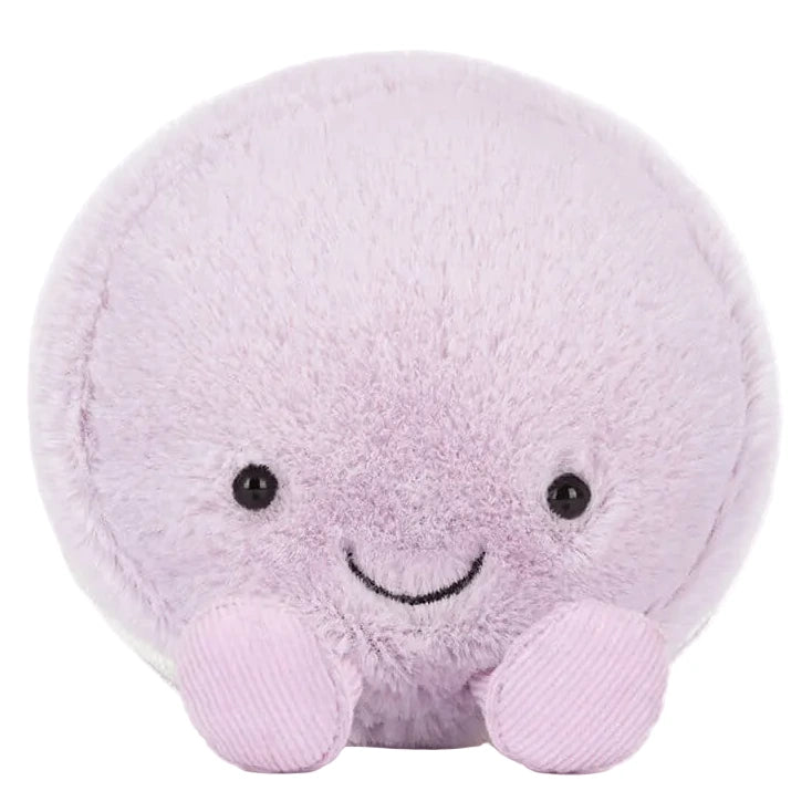 The Jellycat Amuseables May Macaron - Lavender is a round, plush toy with light purple fur, small black eyes, a stitched smile, and two small feet at the front.