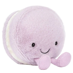 The Jellycat Amuseables May Macaron - Lavender is a plush toy shaped like a lavender macaron, with a smiling face, black eyes, and two small dangling legs.
