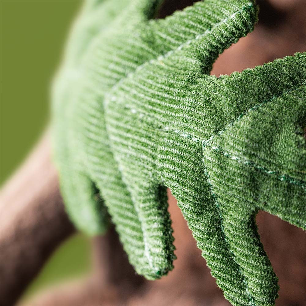 Close-up of someone wearing green, leaf-textured gloves, reminiscent of Jellycat’s Amuseables Ort & Tum Acorns plush toys, set against a softly blurred green backdrop.