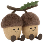 Two Jellycat Amuseables Ort & Tum Acorns plush toys with brown fuzzy caps, smiles, and dangling legs, joined by a soft oak leaf and branch on top.