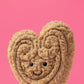 Jellycat’s Amuseables Philippe Palmier is a plush toy featuring embroidered swirls and a smiling face, shown against a plain pink background.