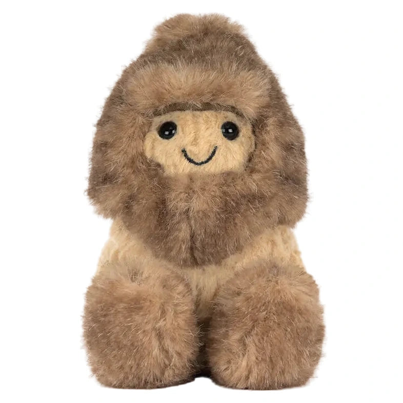 The Amuseables Peanut Yeti Outfit by Jellycat is a plush toy featuring a smiling character in a brown furry parka with a hood, sitting upright—part of Jellycat's cozy collection.
