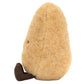 The Jellycat Amuseables Potato is a fluffy, pear-shaped plush toy with golden-brown fur, an upright pose, a small brown corduroy foot, and one visible eye.