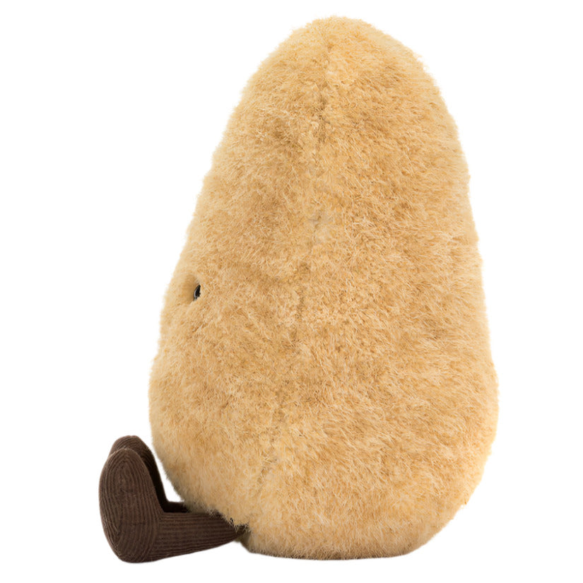 The Jellycat Amuseables Potato is a fluffy, pear-shaped plush toy with golden-brown fur, an upright pose, a small brown corduroy foot, and one visible eye.