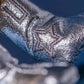 Close-up of the Jellycat Amuseables Peanut Space Rodeo Outfit's silver metallic fabric with a stitched star pattern, highlighting its cosmic flair against a blue background.