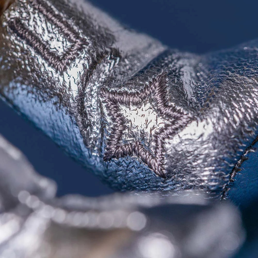 Close-up of the Jellycat Amuseables Peanut Space Rodeo Outfit's silver metallic fabric with a stitched star pattern, highlighting its cosmic flair against a blue background.