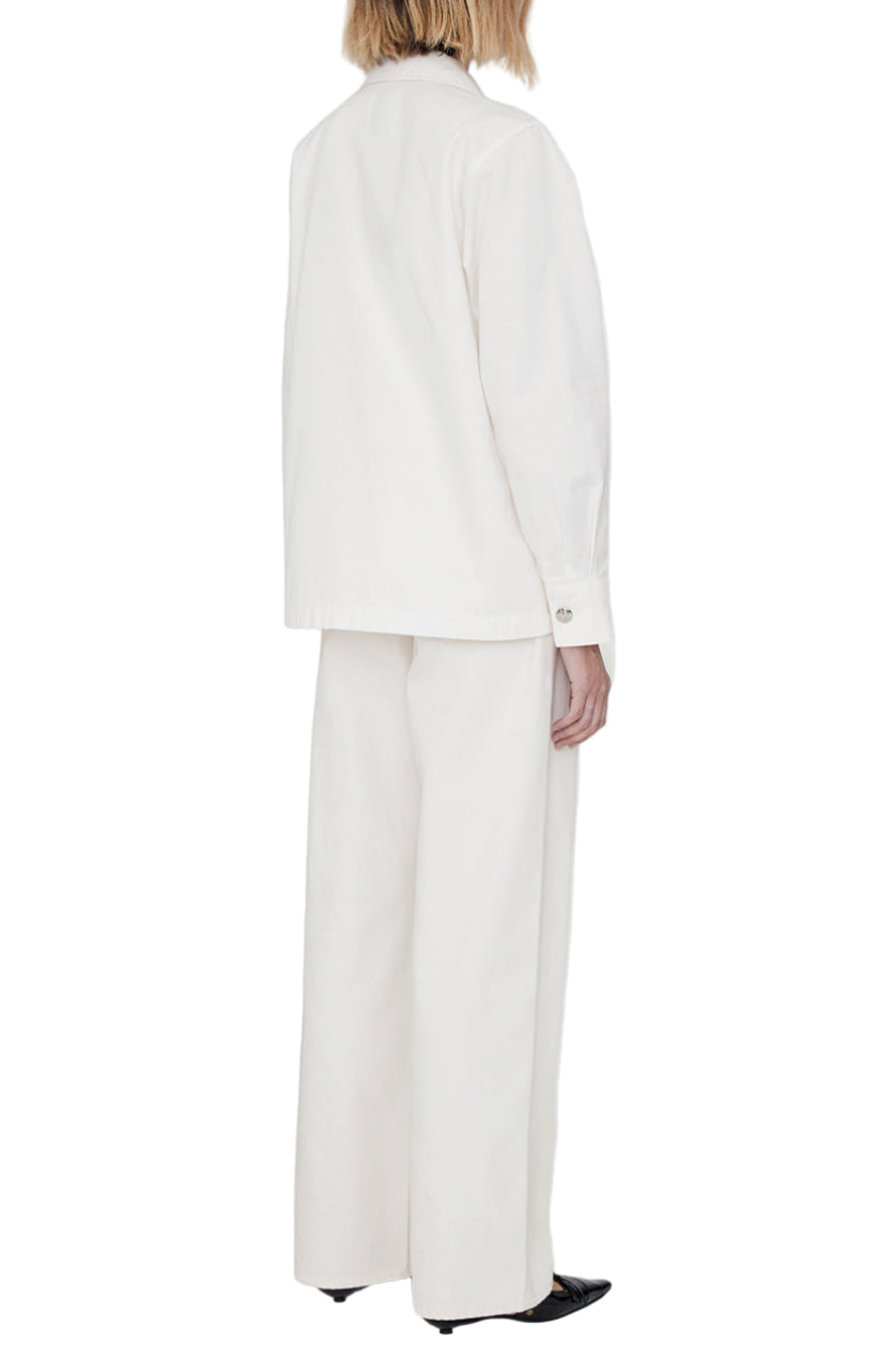 A person stands with their back to the camera, wearing an off-white Anine Bing Corey Jacket and wide-leg trousers with black pointed shoes, set against a plain white background.