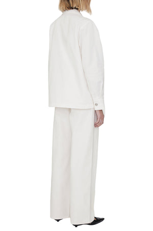 A person stands with their back to the camera, wearing an off-white Anine Bing Corey Jacket and wide-leg trousers with black pointed shoes, set against a plain white background.