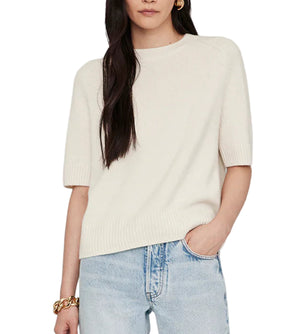 A person wearing the Anine Bing Jackson Sweater, a short-sleeved crewneck in cream, paired with light blue jeans and one hand in their pocket.