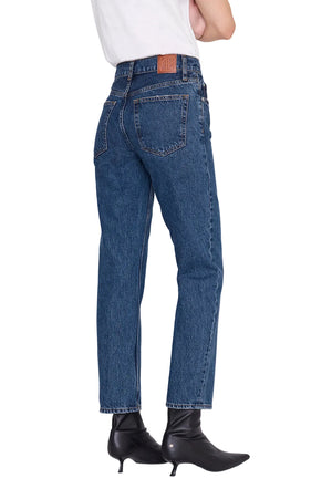 A person is seen from the back against a white background, wearing the Anine Bing Kate Jean—high-waisted jeans crafted from medium blue wash, regenerative cotton denim—paired with a white shirt and black heeled ankle boots.