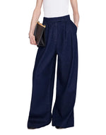 Person wearing the Lou Trouser—wide-leg, high-rise cotton denim dark blue trousers from Anine Bing—and a white sleeveless top, holding a black clutch bag in their right hand.