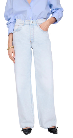 Person wearing a light blue button-up shirt tucked into Anine Bing's Manon Jean—ultra-bleached, high-waisted wide-leg jeans—paired with black pointed-toe shoes for a modern baggy silhouette.