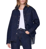 Wearing the Anine Bing Samy Shirt—an oversized dark blue cotton denim canvas shirt—over a white top and matching dark blue denim jeans, with one hand in a pocket.