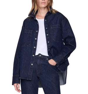 Wearing the Anine Bing Samy Shirt—an oversized dark blue cotton denim canvas shirt—over a white top and matching dark blue denim jeans, with one hand in a pocket.