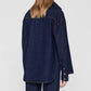 A person with straight, light brown hair is photographed from behind against a plain light background, wearing the oversized Samy Shirt and matching pants by Anine Bing.