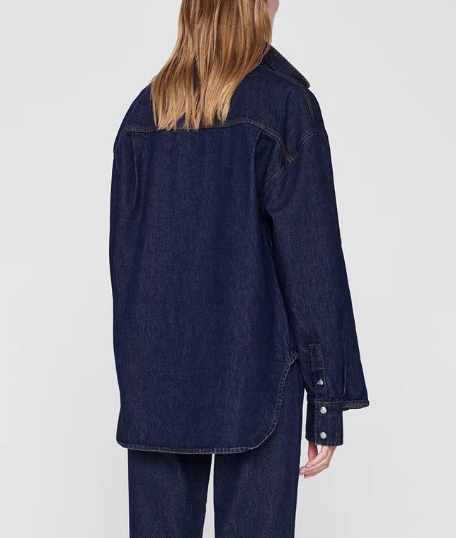 A person with straight, light brown hair is photographed from behind against a plain light background, wearing the oversized Samy Shirt and matching pants by Anine Bing.